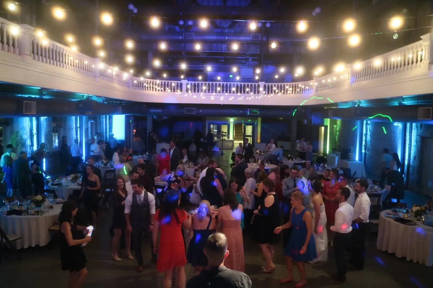 Wedding guests dancing under string lights during an energetic reception with professional DJ entertainment